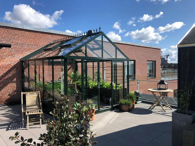 Glasdrivhus ved terrasse og murstenshus